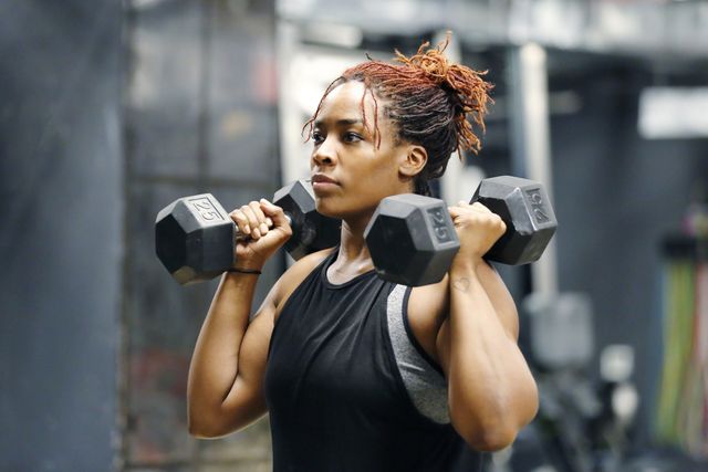 fit, young african american woman working out with hand weights in a fitness gym