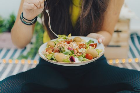 fitness girl eating fresh bowl salad at home