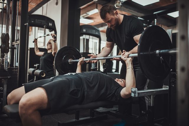 fitness instructor assisting in bench press training
