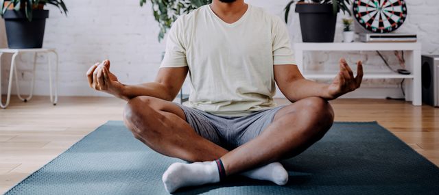 fitness, meditation and healthy lifestyle concept black man meditating in lotus pose on exercise mat at home