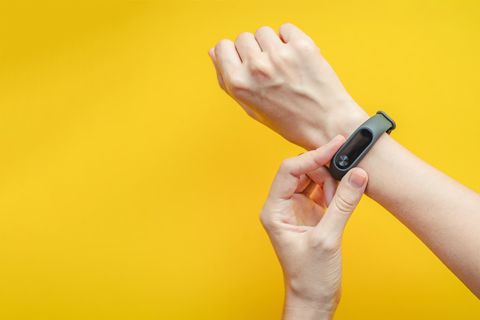 Fitness tracker on woman's hand on yellow background close up