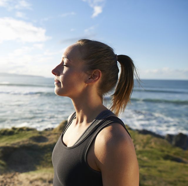 Fitness woman profile with eyes closed beside sea.