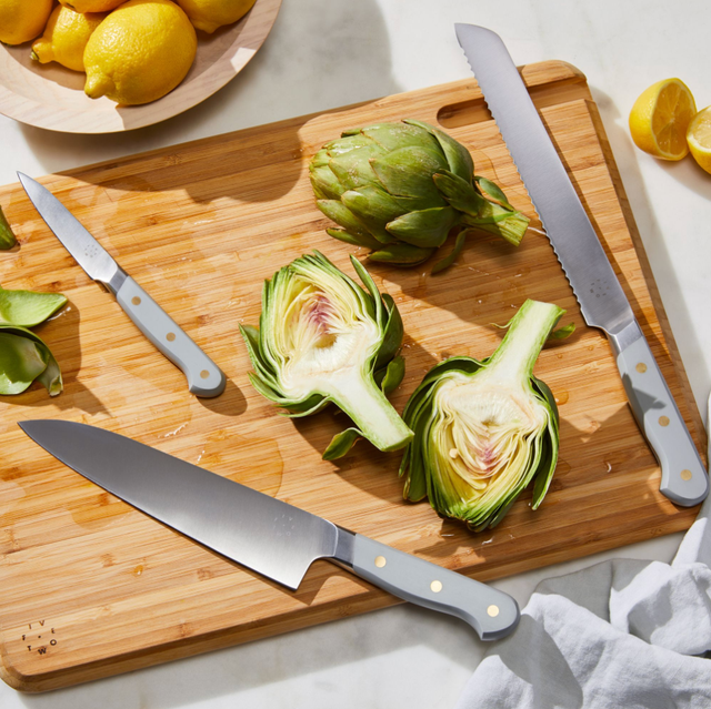 knives on cutting board with halved artichoke