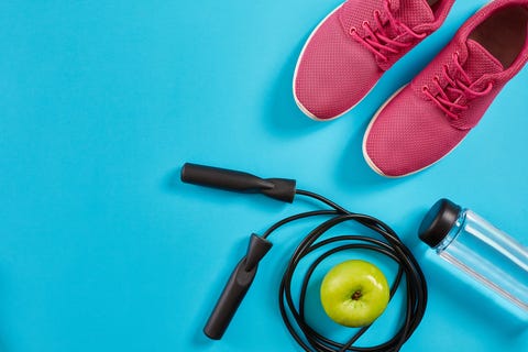 Flat lay of female sport equipments, jump rope, bottle of water and pink sneakers on blue background Flat lay of female sport equipments, jump rope, bottle of water and pink sneakers on blue background