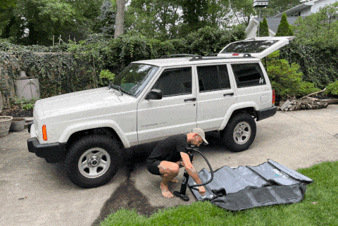 man installing flattened air carrier and putting it on jeep roof