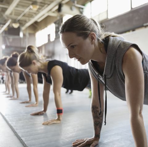 Focused, strong women exercising, doing planks in a row in exercise class
