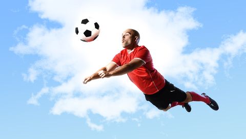 voetballer die in de lucht hangt om voetbal te koppen