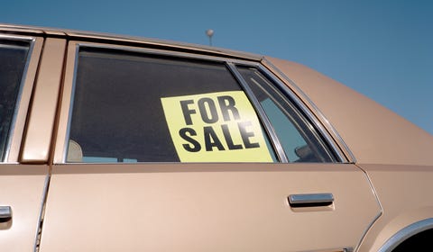 'For Sale' sign placed in car window, outdoors, close-up