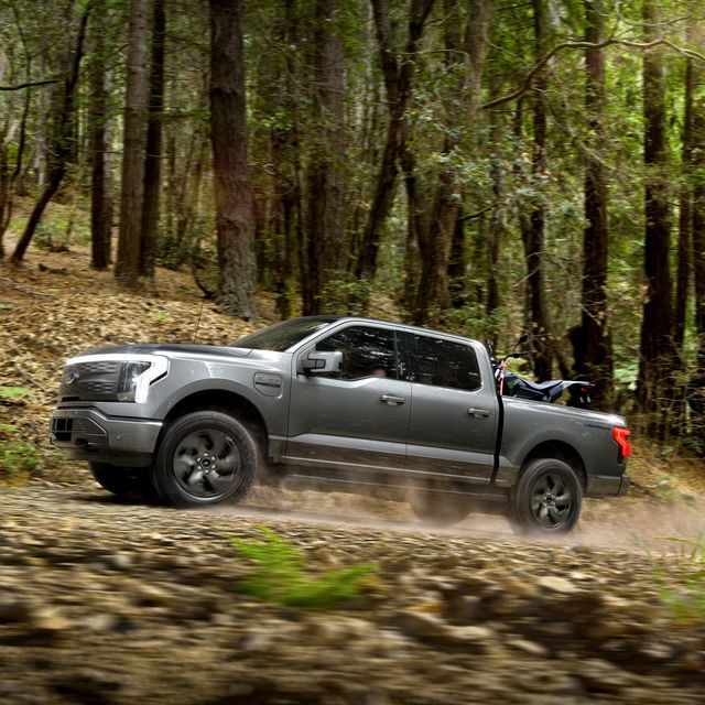 ford f 150 lightning driving in forest with a dirt bike in the bed
