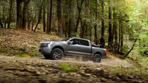 ford f 150 lightning driving in forest with a dirt bike in the bed