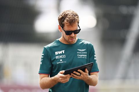 Formel 1 chauffør sebastian vettel, iført solbriller, ser på en tablet, mens han går på en banevandring før en storslået pris
