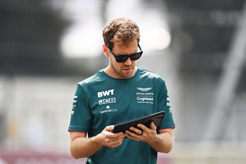 formel 1-föraren sebastian vettel, bär solglasögon, tittar på en surfplatta när han går på en banvandring före en grand prix