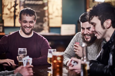 Four friends in a club drinking and playing cards Four friends in a club drinking and playing cards