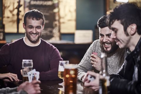 Four friends in a club drinking and playing cards