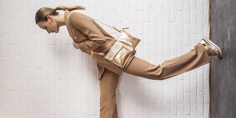 Blond model draagt gouden Fred de la Bretonière sneakers en tas
