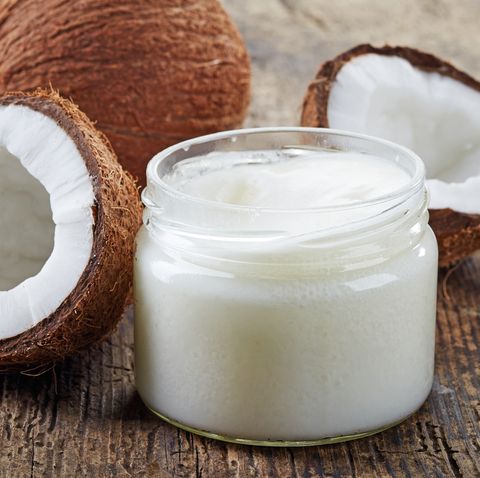 Fresh coconuts and a jar of coconut oil on a wooden table