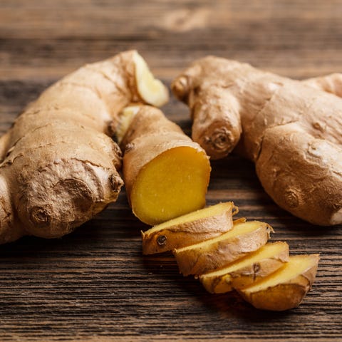 Fresh ginger whole and chopped on rustic wood surface