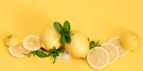 Fresh whole lemons and slices on the yellow background