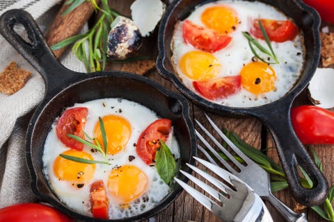 Fried eggs with tomatoes in frying pans served for breakfast