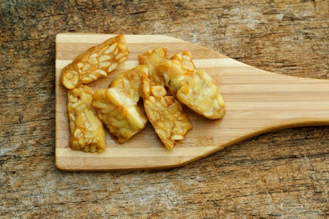Fried Tempeh in wooden spatula on textured background Fried Tempeh in wooden spatula on textured background
