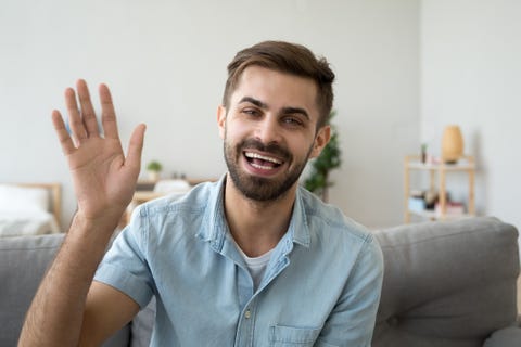 friendly happy man waving hand saying hello looking at camera