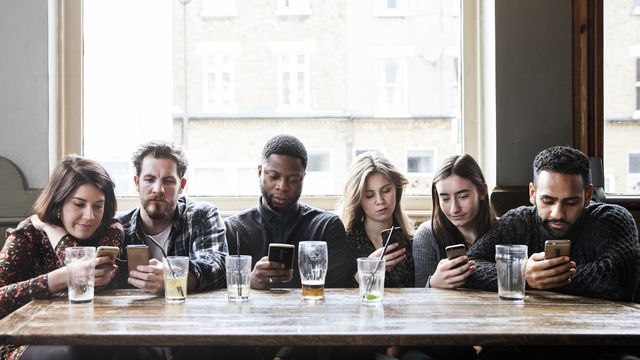 6 friends at a pub with phones