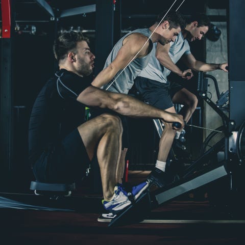 Effective Rowing Machine Workout Friends training in male fitness club