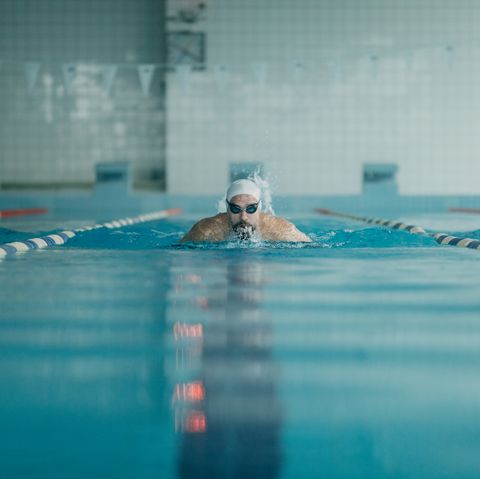 front view of professional swimmer swimming in indoors swimming pool