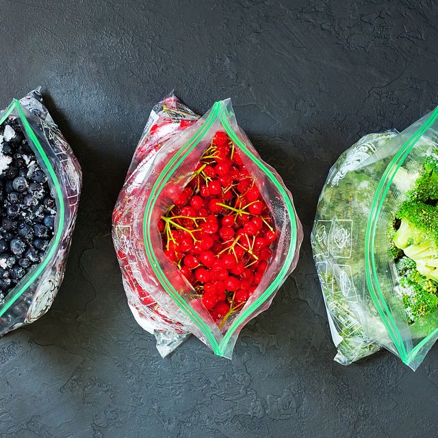 frozen berries and vegetables in bags in packages on dark concrete background   close up