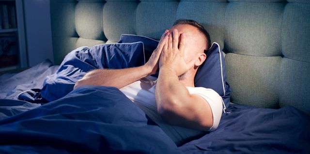 frustrated man fighting with sleeping disorder holding head in hands