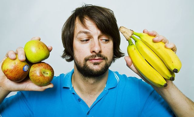 un hombre decide si las manzanas o los plátanos son mejores para su dieta con síndrome del colon irritable