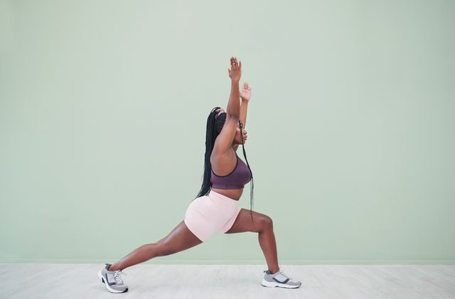 full body studio shot of a young woman exercising against a green background