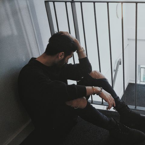 Full Length Of Depressed Man Sitting By Railing In Building