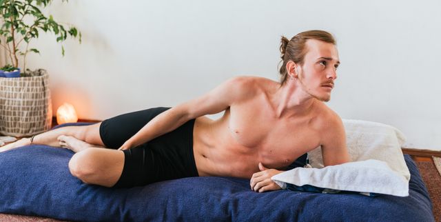 full length of shirtless man lying on mattress against wall
