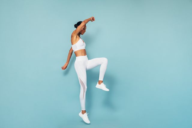 full length of woman exercising against blue background