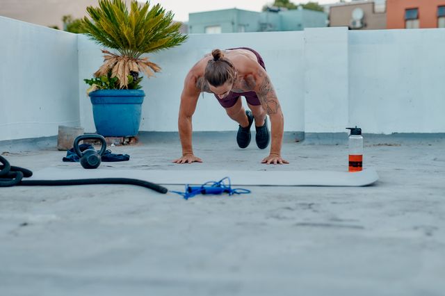 full length shot of a handsome young man doing burpees during a workout on the rooftop