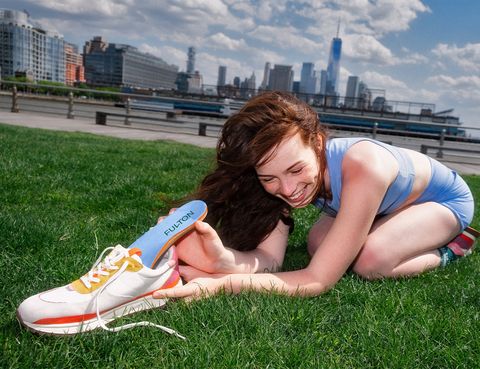 bir ayakkabının iç tabanını koyarak çimenlerin üzerinde oturan bir kadın