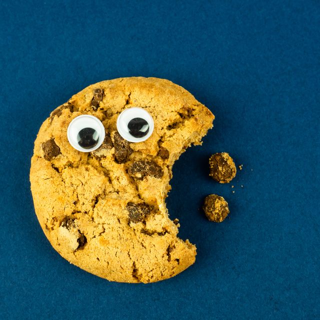 funny food concept a chocolate chip cookie with eyes with a bite against a blue background