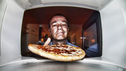 man stopt pizza in magnetron