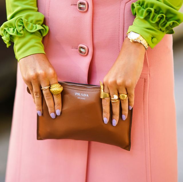 gabrielle berdugo draagt gouden ringen met pastelkleurige lila nagellak en een groene blouse, roze rok tijdens fashion photo session in parijs 2020