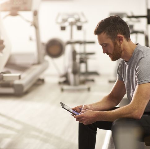 un hombre usa una tableta digital como gadget para su entrenamiento en el gimnasio