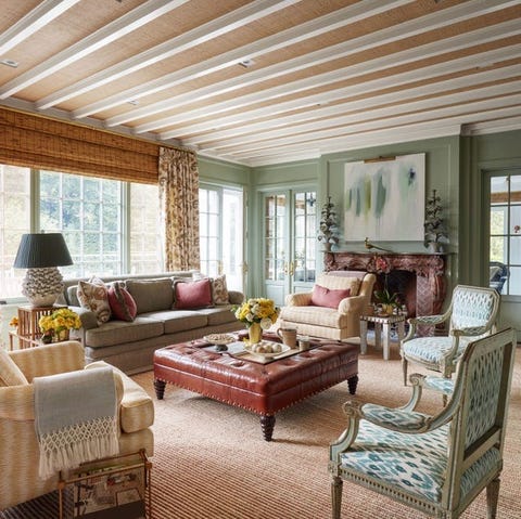 living area with sofa tufted leather ottoman as a coffee table upholstered armchairs and fireplace in the background