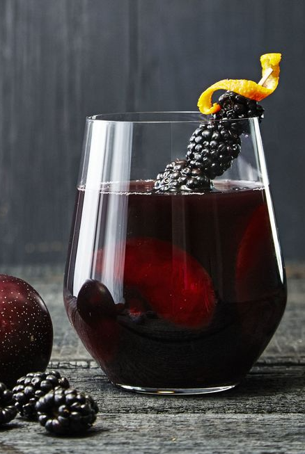 black magic punch with blackberry garnish on a black table