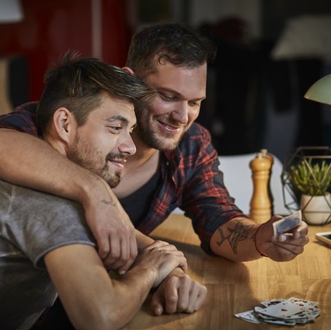 Gay couple hugging at table with playing cards