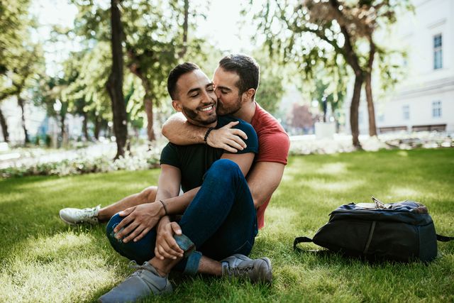 gay couple latino and european millennial men  enjoying in park in summer