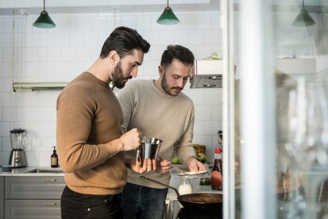 Gay couple preparing food in kitchen at home Gay couple preparing food in kitchen at home