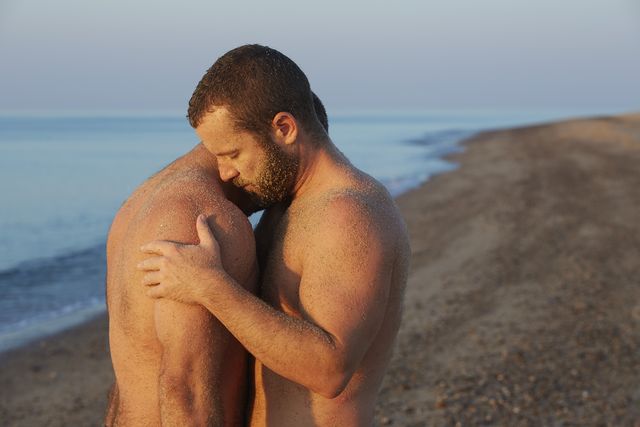 gay male couple embrace on beach