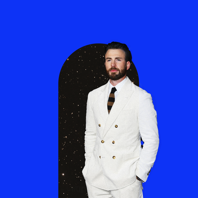 chris evans in a white suit stands over a keyhole shaped starry sky print over a deep blue background