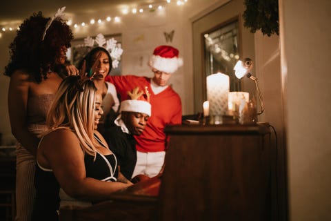 generation z friends christmas party singing at piano