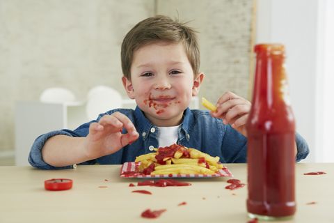 Germany, Munich, Boy eating French fries with ketchup